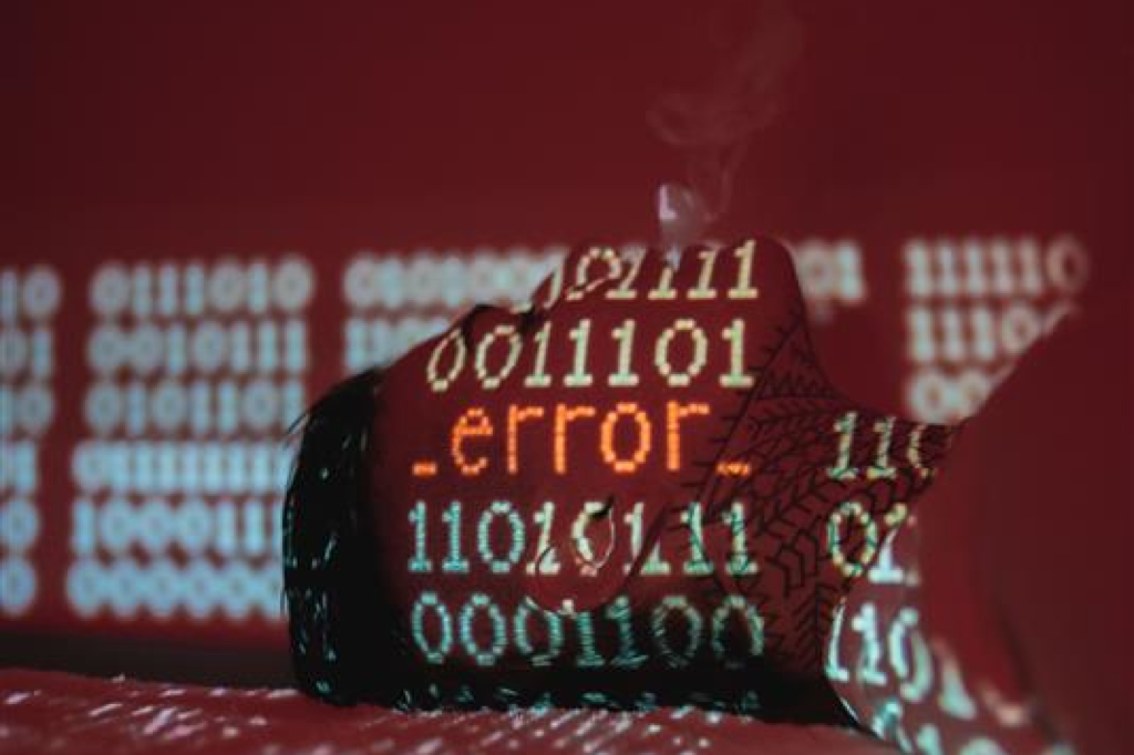 The Compliance Cliff article cover: binary code and the word .error. projected onto a person's face in red light
