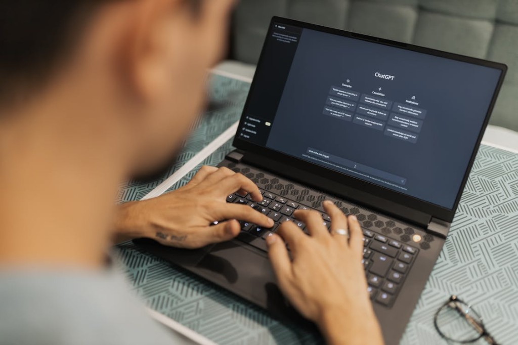 Over-the-shoulder view of a person typing a query into the ChatGPT interface on a laptop, illustrating AI-powered search and generative engines