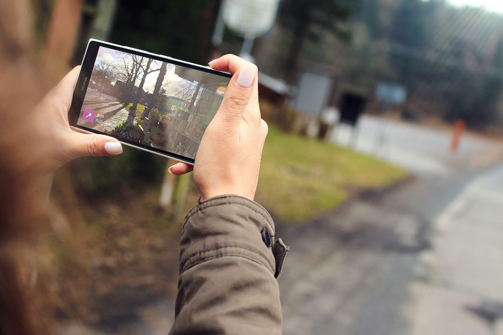 Spatial UX article cover: a person viewing an outdoor scene through a smartphone screen, a bounded rectangle that spatial computing removes
